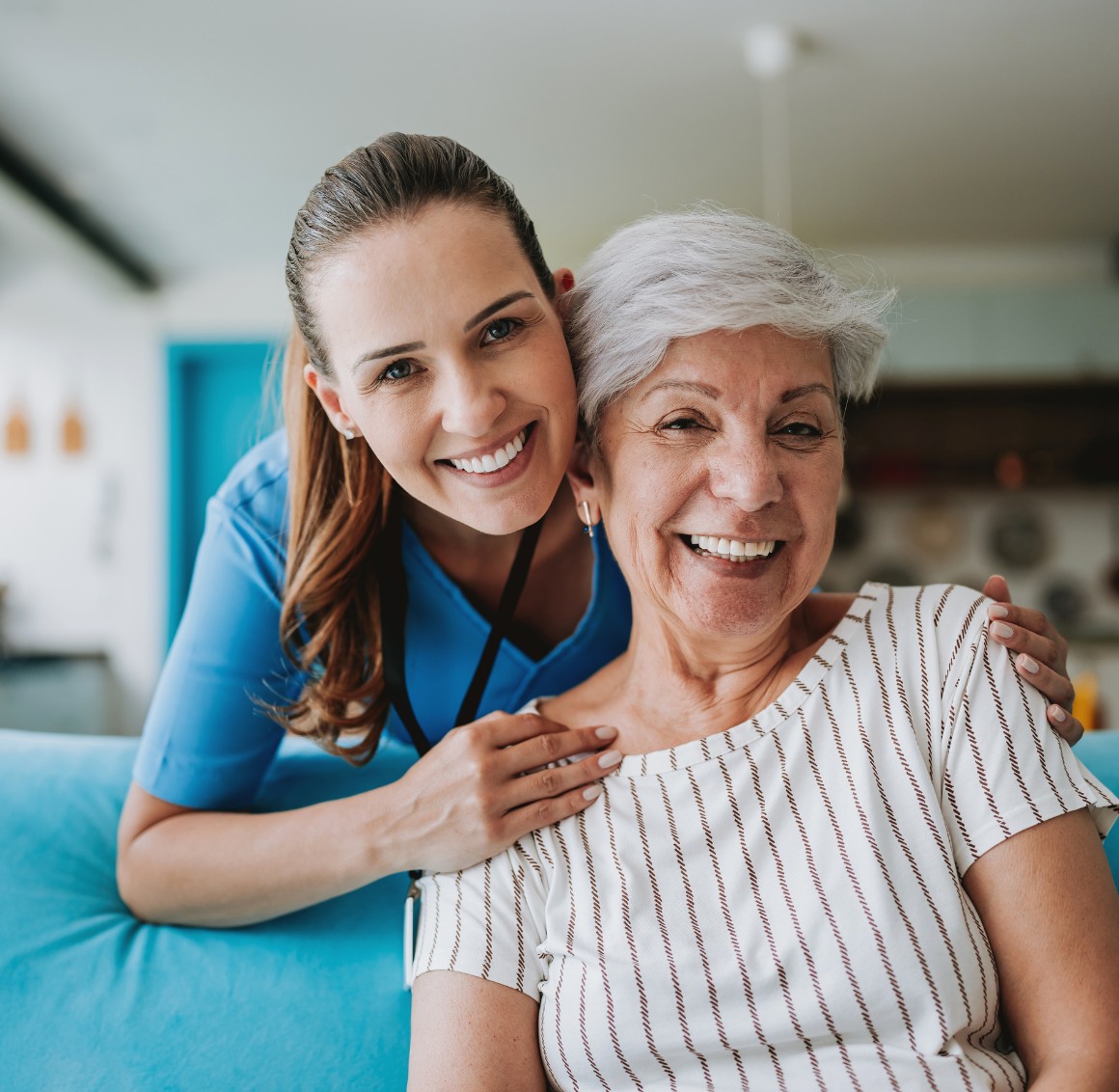 Caregiver hugging senior woman on couch